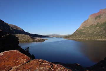 Serene lake surrounded by mountains under clear blue sky