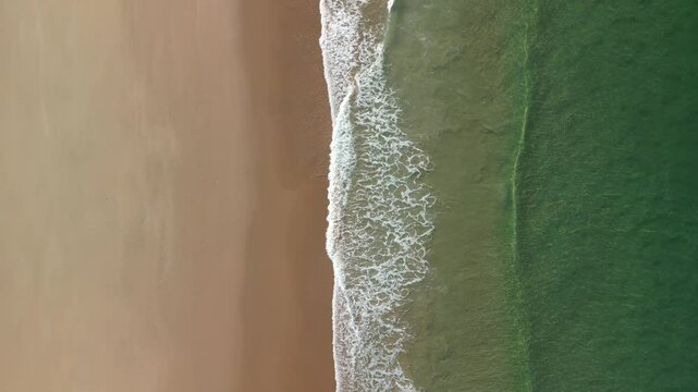 Aerial view of sand beach with Atlantic ocean's waves in the small town Trafaria, Lisbon, Portugal