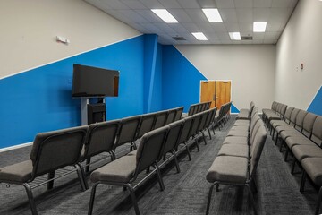 Empty conference room with rows of chairs and TV screen