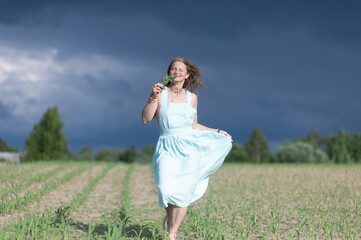 Woman walking in a field under a dramatic sky