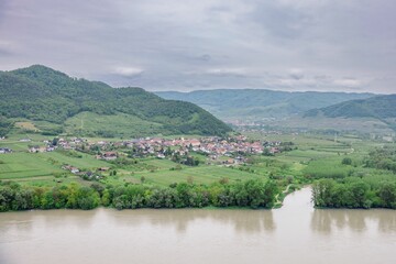 Aerial view of a village by a river with green hills