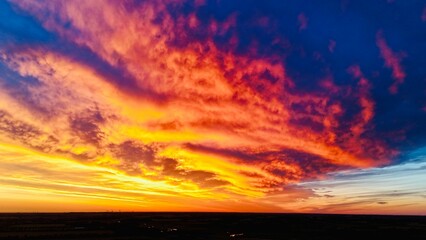 Vibrant sunset with fiery red, orange, and pink clouds against a blue sky.