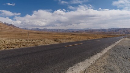 Empty highway through barren landscape with mountains