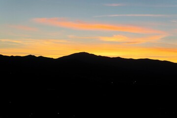 Fototapeta premium Silhouette of mountains against a vibrant sunset sky with orange and blue hues