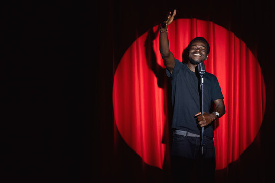 African american man comic with old microphone on theater stage on red curtains background. Concept banner standup comedian show