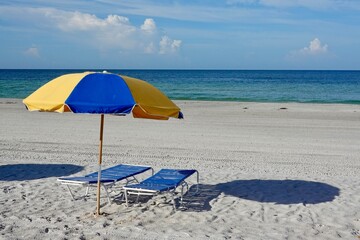 Blue and yellow beach umbrellas in the sand on a beach.