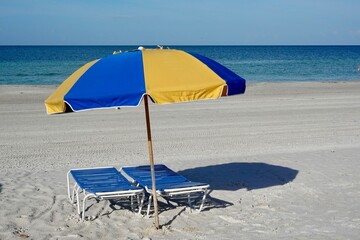 Blue and yellow beach umbrellas in the sand on a beach.