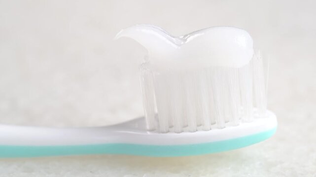 Putting whitening toothpaste on a toothbrush on white background. Applying a swatch of whitening toothpaste on brush.
