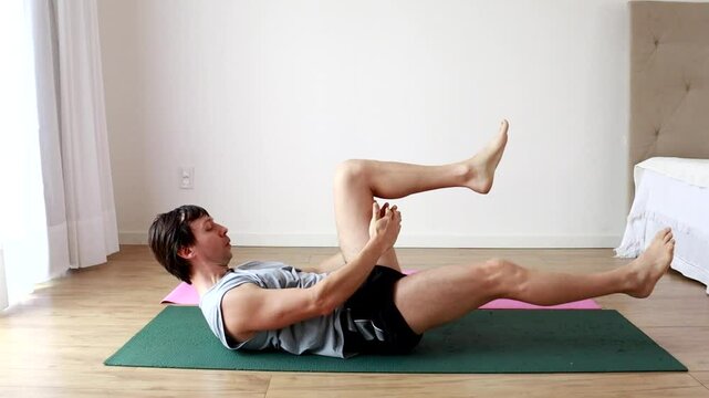 homem fazendo exerc&iacute;cios para abdomen e pernas em casa 