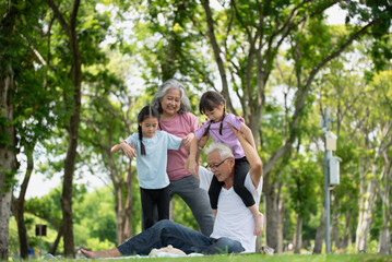 Fototapeta premium Happy Asian family children having fun and playing with her grandparents in the park