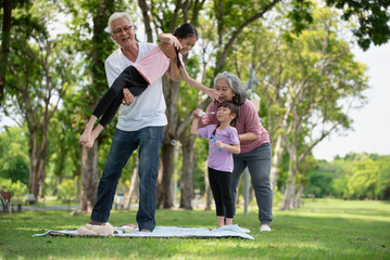 Happy Asian family children having fun and playing with her grandparents in the park