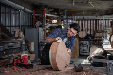 Luthier creating a guitar and using tools in a traditional