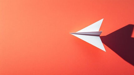 A single white paper airplane flying across a bright coral background, symbolizing joy and freedom with minimalist design and clean shadows