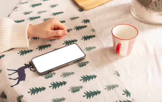 Mobile phone screen mockup on Christmas table, cozy mug at home.