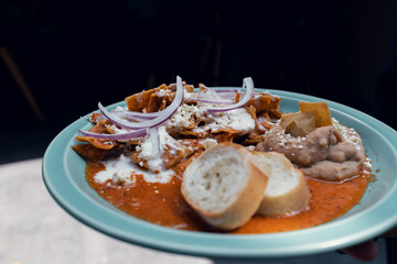 Platillo Mexicano chilaquiles con carne de puerco acompañado de frijoles y pan