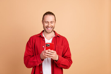 Photo of nice young man use phone empty space wear red shirt isolated on beige color background
