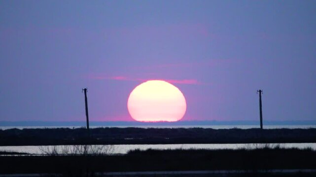 Set of the full moon, moonset, the upper part of the moon on the horizon, phases of the moon, plenilune. Morning twilight view of the lake, the moonlight lends enchantment to the landscape