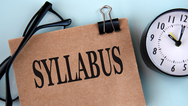 SYLLABUS - word on brown paper on a light background with glasses and a clock