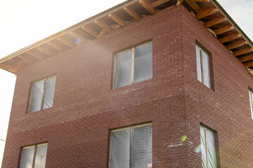 Unfinished two-storey brick house. Construction film on windows  
