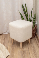 White square pouf with faux fur upholstery. Pouf in bedroom. Vertical