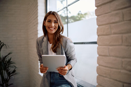 Portrait of happy businesswoman using touchpad in office and looking at camera.