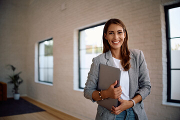 Portrait of young happy businesswoman in office looking at camera.