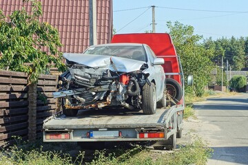 one  gray  expensive passenger broken iron car after the accident   stands on an old gray tow truck...