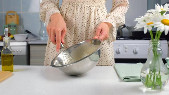Woman cooking homemade mayonnaise sause whisking ingredients in metal bowl, hands close-up. Cooking sauce for salad, meat dishes. Dressing for different dishes. Culinary, cuisine, baking concept.