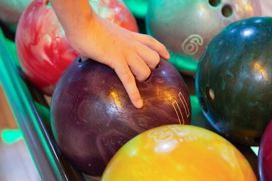 Close-up of hands picking colorful bowling balls