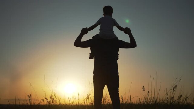 Father carries child on shoulders. Family enjoys scenic sunset walk. Silhouette family bonding at sunset. family moments during sunset walk. Child father shoulders at sunset. Family shoulder in nature