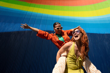 Joyful lesbian couple celebrating under colorful backdrop