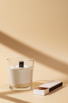 Minimalist scented candle and matchbox on soft beige background