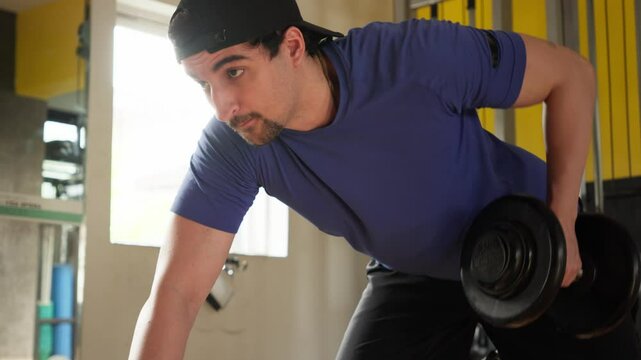 Focused Man Performing Back Exercise in Gym. Man Engaged in Weight Training, Executing a Back Workout with Intensity in a Fitness Environment