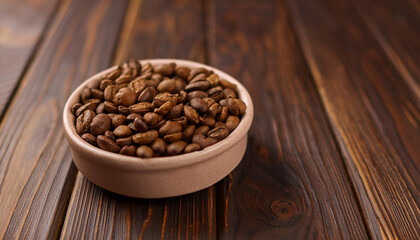 Fototapeta premium Roasted coffee beans in ceramic bowl on dark wooden table. Tasty and aromatic beverage.