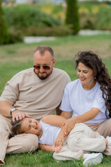 happy family is relaxing on a green lawn in the park in summer