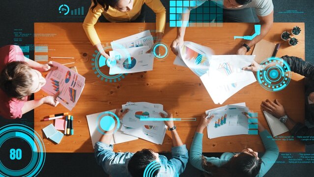 Top view of start up business team holding paper while discussing about financial idea. Aerial view of smart diverse people brainstorming idea about financial graph and stock market chart. Symposium.
