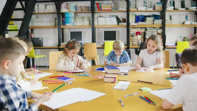 A vibrant and lively classroom environment where enthusiastic children are engaged in drawing and learning collaboratively at a large table