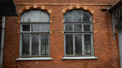 There are two elegantly arched windows located on a red brick building