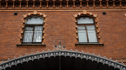 A brick building with elegant arched windows and a wrought iron arch