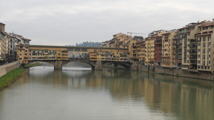 Obraz premium Florence, Italy - decembre 27 2024: Sunny Tuscany with iconic Ponte Vecchio, Florence skyline historic architecture, Arno River reflections. A colorful blend of Renaissance culture, medieval landmarks