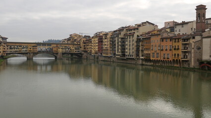 Obraz premium Florence, Italy - decembre 27 2024: Sunny Tuscany with iconic Ponte Vecchio, Florence skyline historic architecture, Arno River reflections. A colorful blend of Renaissance culture, medieval landmarks