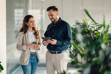 Smiling colleagues with tablet at modern office collaborating on project