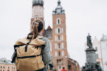Tourist happy woman posing on Market Square in Krakow, Traveling Europe in autumn. St. Marys Basilica, no face, rear view