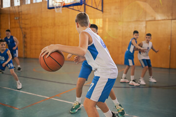 Naklejka premium Young basketball player leading with the ball