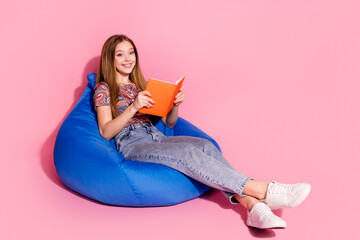 Full length photo of lovely teen lady sit bean bag read book dressed stylish print clothes isolated on pink color background