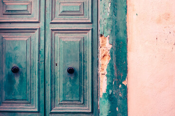 Damaged and ruined old green wooden door detail in an architecture still in Gozo, Malta