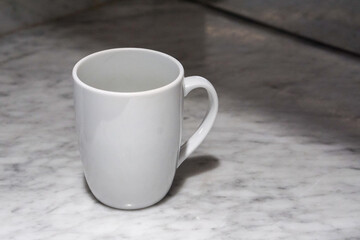 A white coffee cup sits on a marble table.