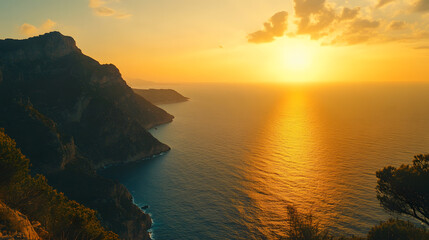 Fototapeta premium A majestic ocean view from a mountaintop with the sun setting over the sea and casting a golden glow on the water.
