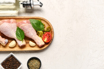 Composition with raw chicken legs, spices and oil on light background
