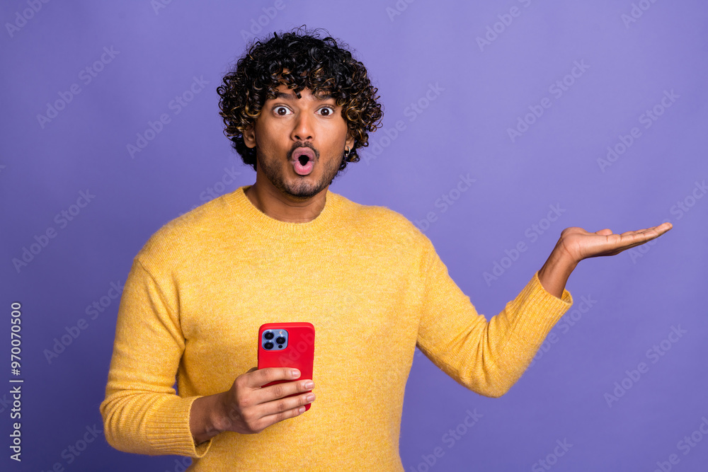 Wall mural Photo of impressed man user wear trendy yellow sweatshirt arm hold empty space isolated on violet color background